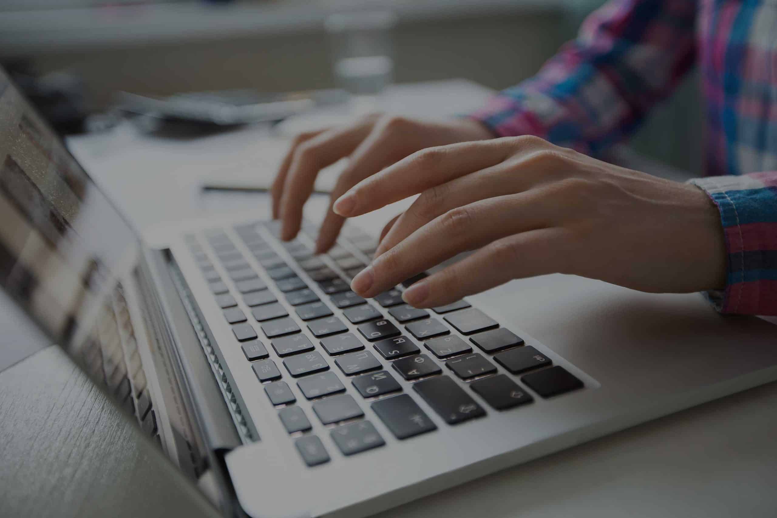 Cropped View Of Hands Typing On Laptop